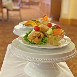 A beautifully presented plate featuring a pastry, fruit cup, and garnished salad.