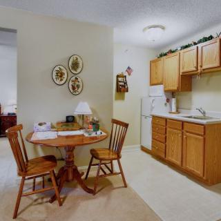 A cozy kitchen with wooden cabinets and a small dining area, featuring a round table and two chairs.