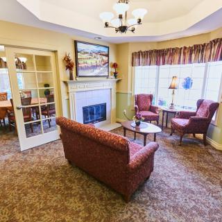 A cozy living room with a fireplace, comfortable seating, and large windows.