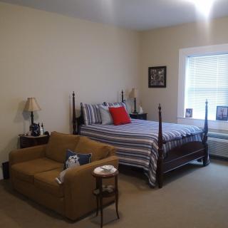 A cozy bedroom with a bed, sofa, and lamp next to a window.