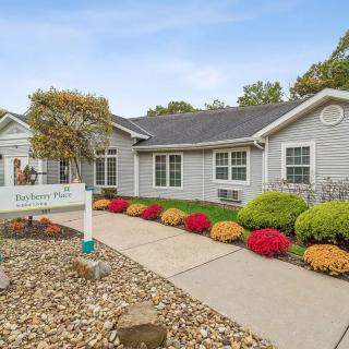 A well-maintained house with a beautifully landscaped front yard featuring colorful flowers and bushes along a paved pathway.