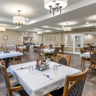A well-lit dining area featuring neatly arranged tables and chairs with simple decor.