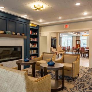 A cozy lounge area featuring comfortable seating, a fireplace, and a small library with modern decor.