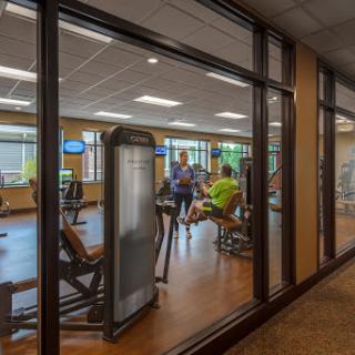 A view of a gym with various exercise equipment and individuals engaging in workouts.