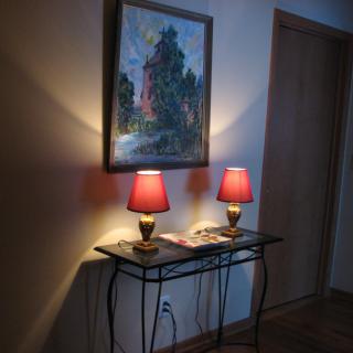 A cozy corner featuring two red lamps on a table beneath an impressionist-style painting.