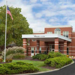 A hospital building with a landscaped entrance and American flag.