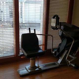 A view of exercise equipment set up in a home gym with natural light coming through the window.