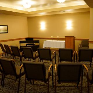 An empty meeting room set up with chairs facing a podium and table with candles.