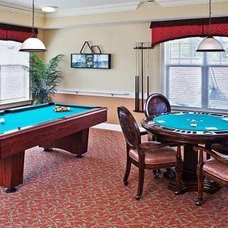 A cozy gaming room featuring a pool table and a card table with chairs, designed for leisure and relaxation.