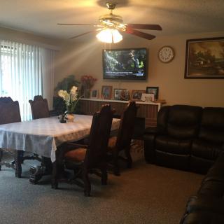 A cozy living and dining space featuring a table with chairs, a sofa, and a television mounted on the wall.