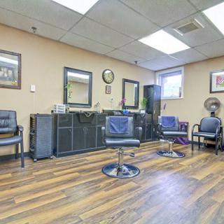 A modern salon interior featuring chairs, mirrors, and wood flooring.