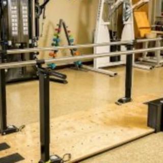 A rehabilitation area featuring parallel bars and gym equipment.
