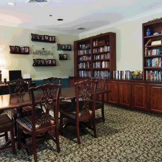 A cozy library room with wooden furniture and bookshelves lining the walls.