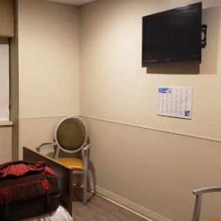 A simple hospital room featuring a bed, a television mounted on the wall, and a chair.