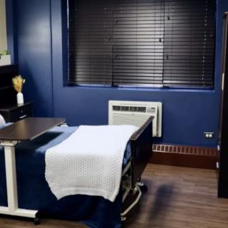 A neatly arranged room with a hospital bed, blue walls, and window blinds.