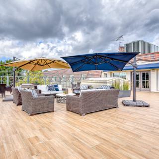 A spacious outdoor patio with modern wicker furniture and large umbrellas under a cloudy sky.