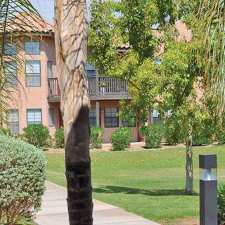 A view of an apartment building surrounded by lush green landscaping and a pathway.