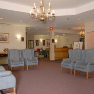 A spacious lobby featuring comfortable seating, chandeliers, and a reception desk.