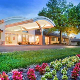 A well-lit building entrance surrounded by colorful flowers and greenery in the evening.