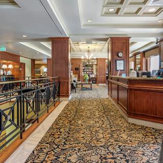 A luxurious hotel lobby featuring a reception desk, elegant carpeting, and a chandelier.