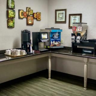Office breakroom coffee station with multiple beverage dispensers and decor.