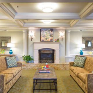 A cozy living room featuring elegant sofas, a central coffee table, and a classic fireplace with delicate lighting.