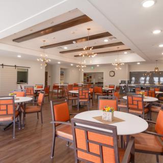 A modern dining area with orange chairs and white tables, featuring elegant lighting and contemporary decor.