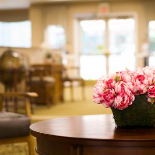 A cozy lounge area featuring a wooden table adorned with a vibrant bouquet of pink flowers.