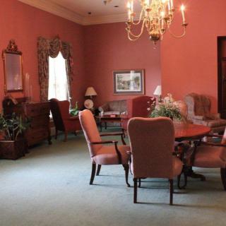 A traditional dining room with pink walls, an elegant chandelier, and classic furniture.