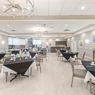 A modern dining area featuring elegantly arranged tables with black tablecloths and stylish chairs.