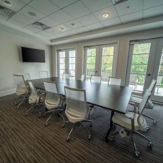 A modern conference room with a large table, chairs, and a television.