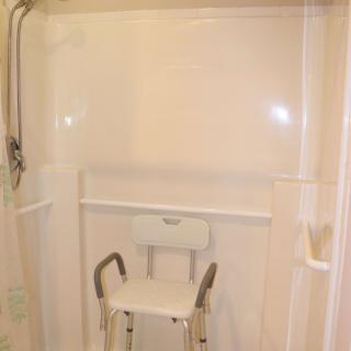 A bathroom shower equipped with a safety chair for accessibility.