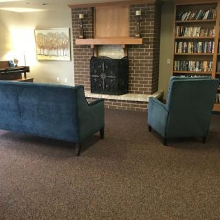 A cozy living room with blue sofas facing a fireplace and surrounded by bookshelves.