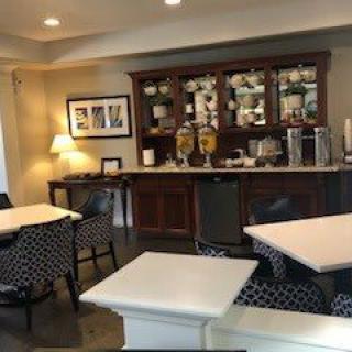 A cozy dining area with tables, chairs, and a beverage station.