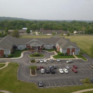 An aerial view of a residential building with a parking lot surrounded by greenery.