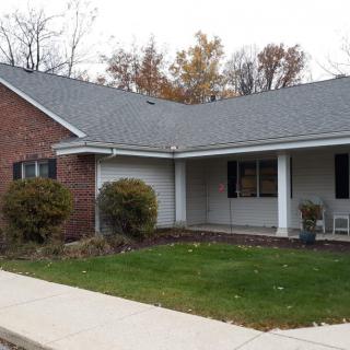 A suburban brick house with a small porch and lawn.