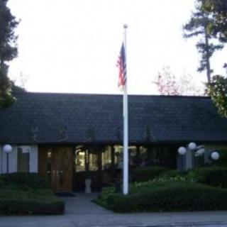 A building with a flagpole displaying the American flag in front, surrounded by trees.