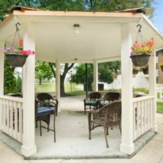 A cozy garden gazebo with outdoor seating and hanging plants.