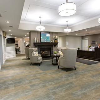 A cozy and warmly lit lobby area with plush chairs, a fireplace, and a reception desk.