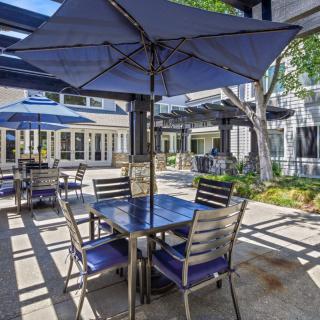 A cozy outdoor patio with tables, chairs, and large umbrellas providing shade.