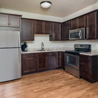 A modern kitchen with stainless steel appliances and wood flooring.