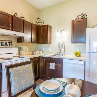 A cozy kitchen with dark wooden cabinets, a dining table set, and various appliances.