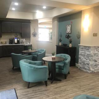 A cozy lounge area featuring modern decor with teal chairs and round tables.