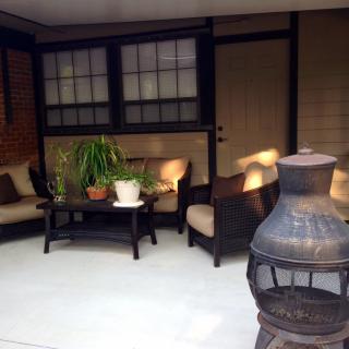 A cozy patio with comfortable seating, a chiminea, and plants creating a welcoming outdoor space.
