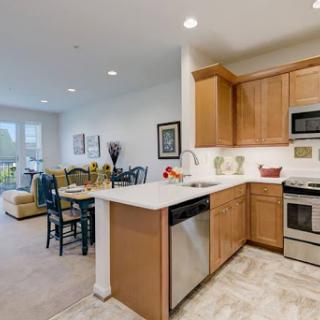 A modern kitchen featuring wooden cabinets and stainless steel appliances, seamlessly connected to a cozy dining area.