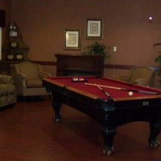 A cozy game room featuring a pool table with red felt and comfortable seating.