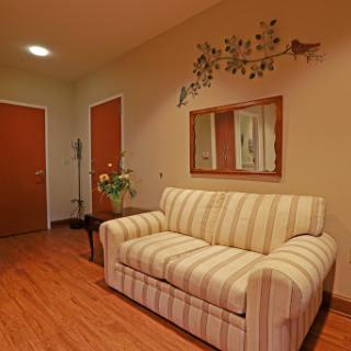 A cozy living room featuring a striped sofa, decorative wall art, and wooden floors.