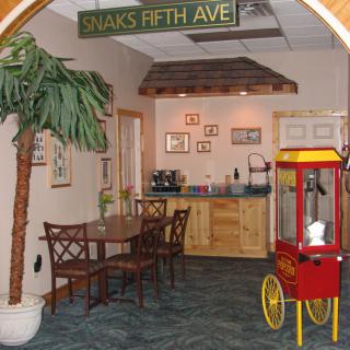 A cozy snack area featuring a popcorn machine, decorative plants, and seating.