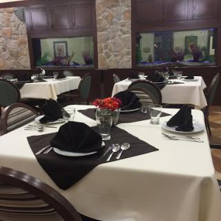 An elegantly set dining table in a restaurant, featuring black napkins and a floral centerpiece.
