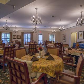 An elegant dining room with multiple tables and chandeliers, showcasing a well-decorated interior.